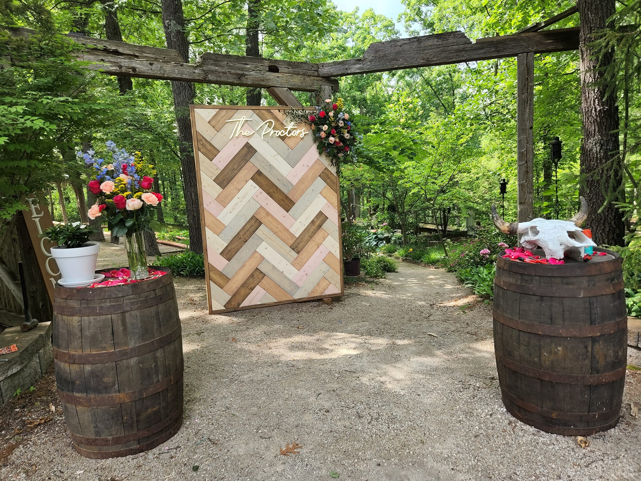 wooden photo backdrop and whiskey barrel decor at outdoor wedding
