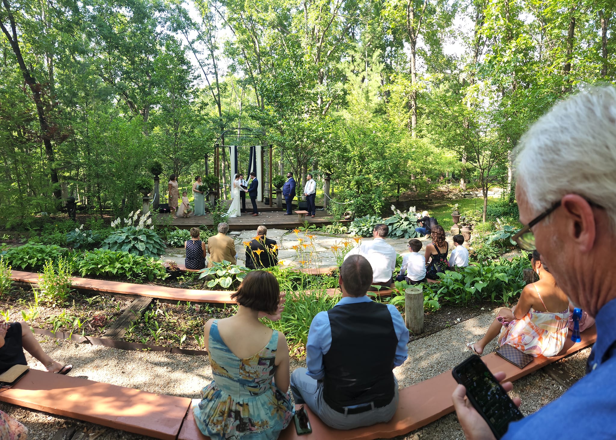 guests sitting on benches during garden wedding